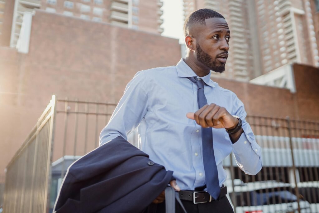 Stylish businessman in city street checking the time, wearing suit and tie.